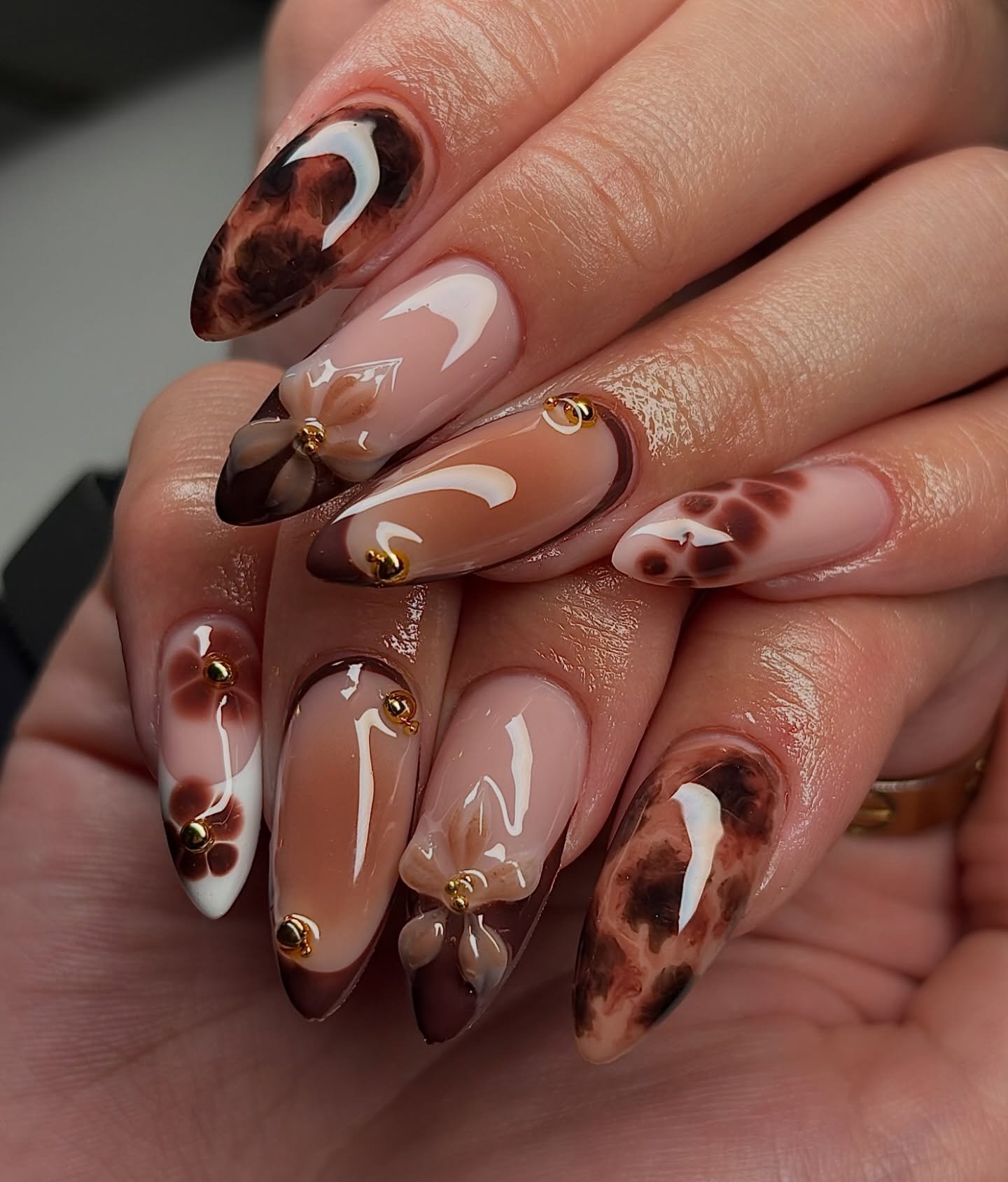Brown Almond Nails with Cream Swirls and Small Floral Details