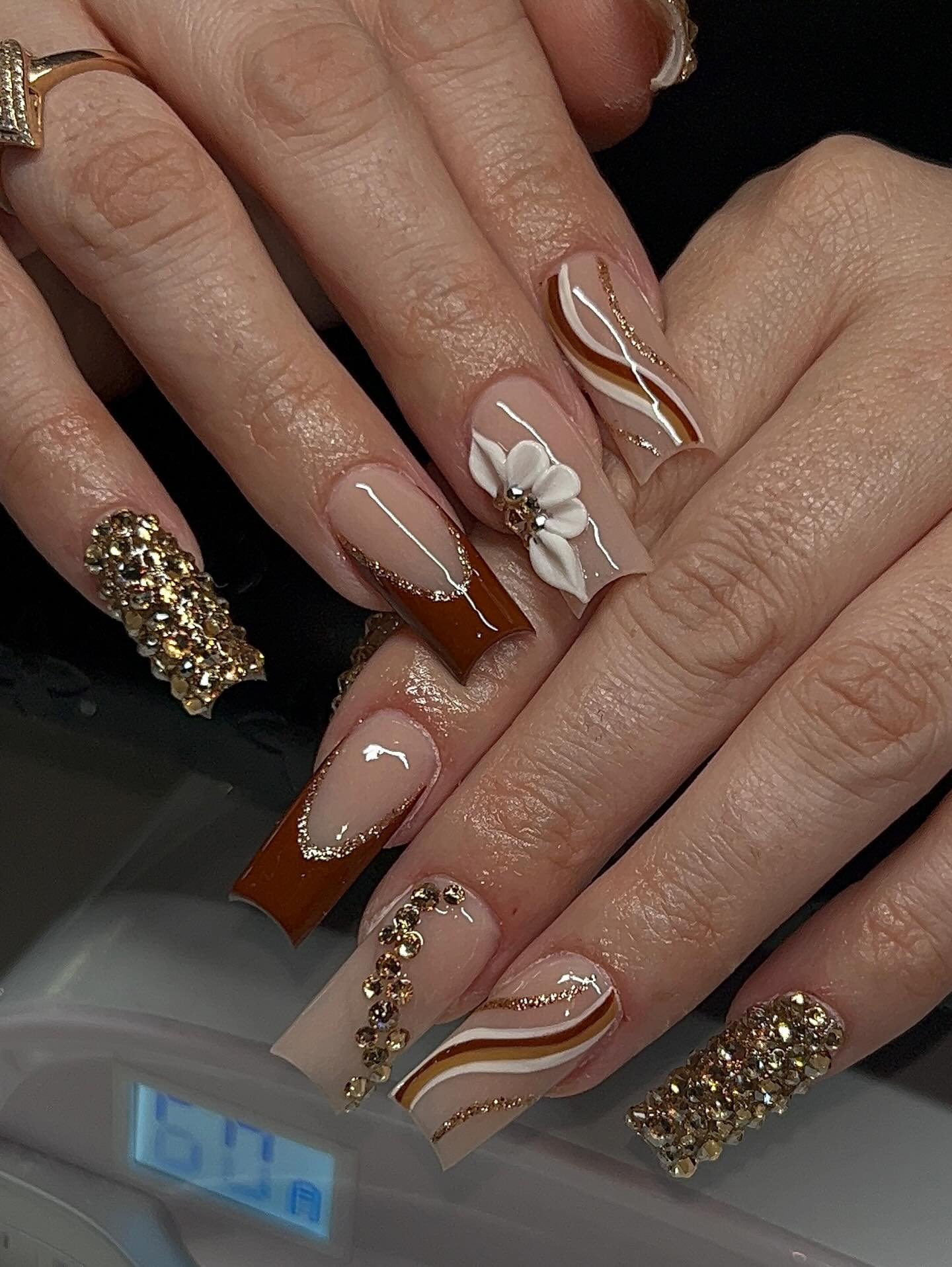 Nude Almond Nails with White Floral Details and Gold Glitter