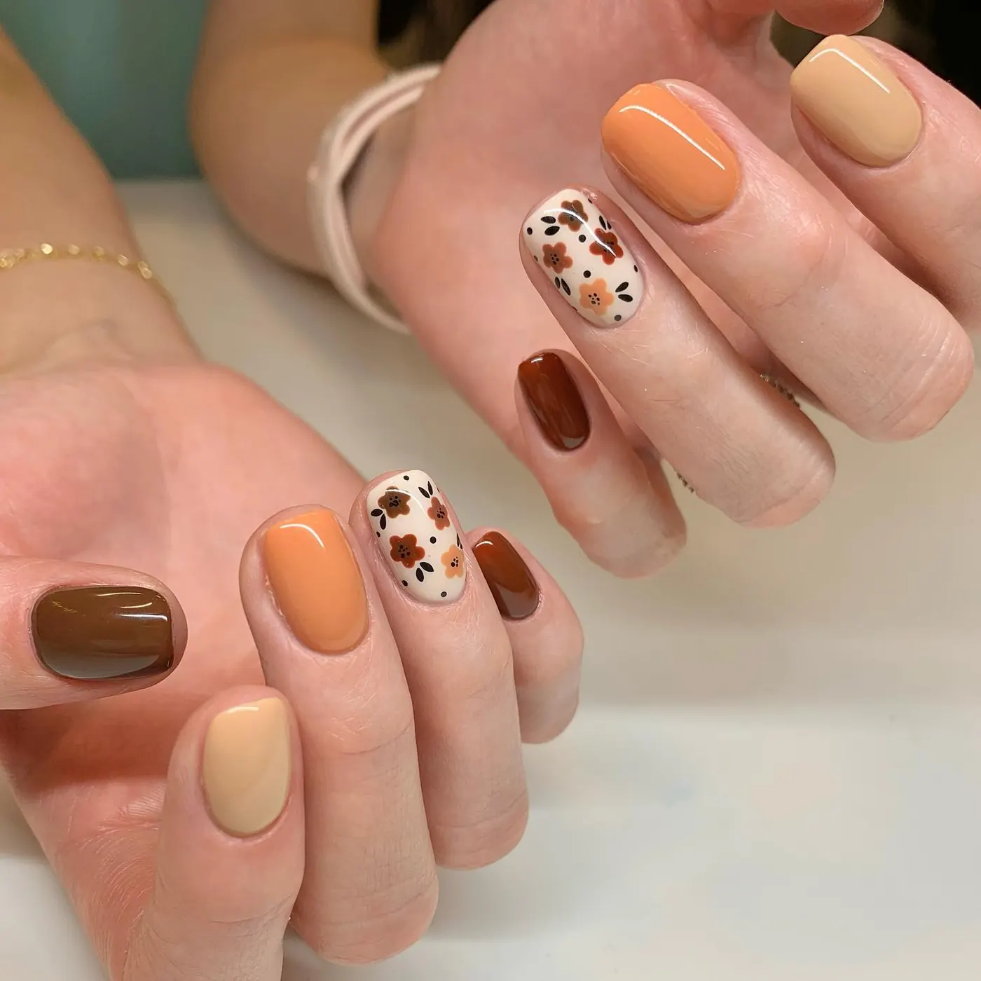 Orange, Brown, and Cream Nails with Speckled Floral Accents