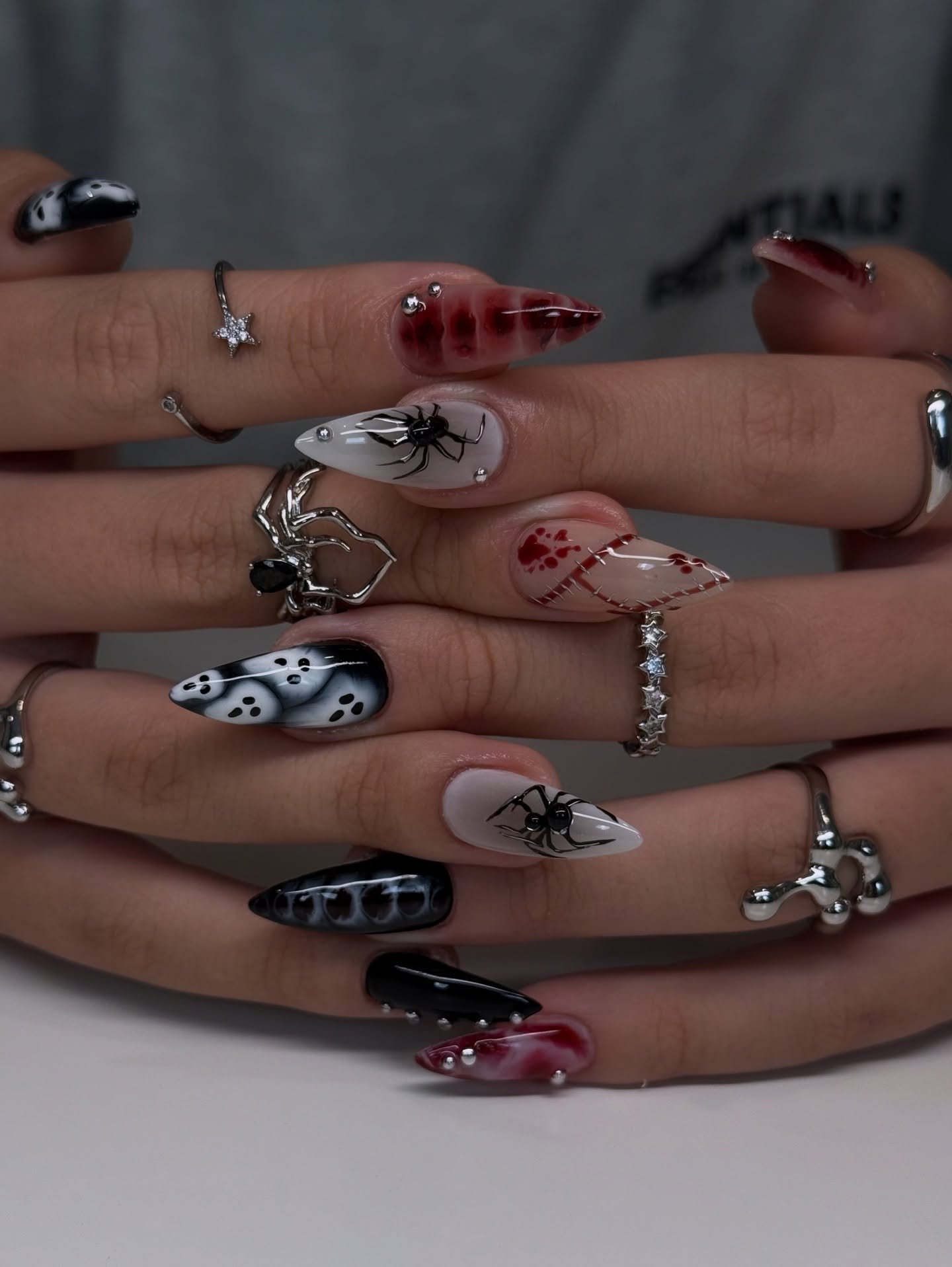 A mixed Halloween manicure combines black, red, white and metallic-looking details with varied spooky motifs across the nails.