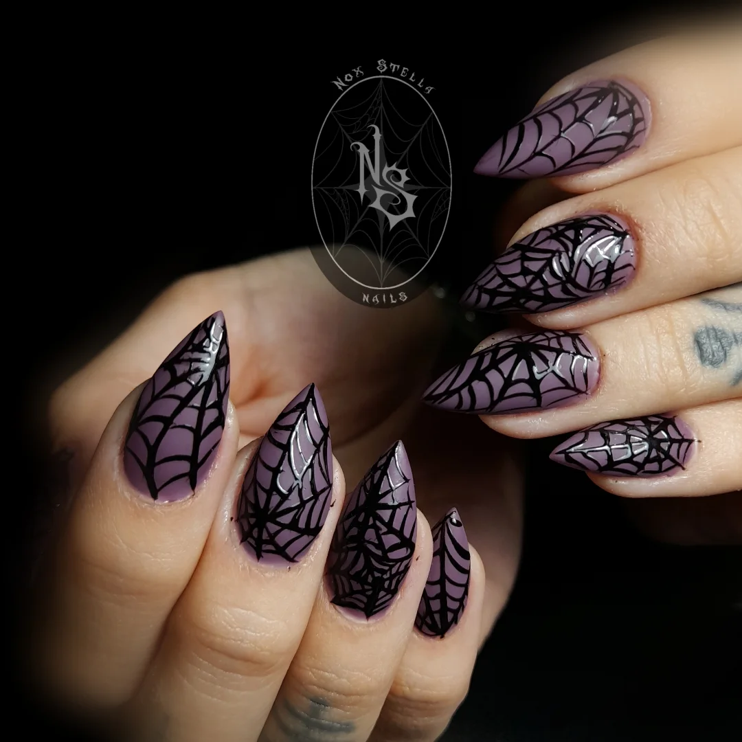 Pointed lavender nails are covered with crisp black spiderweb patterns for a simple gothic Halloween look.