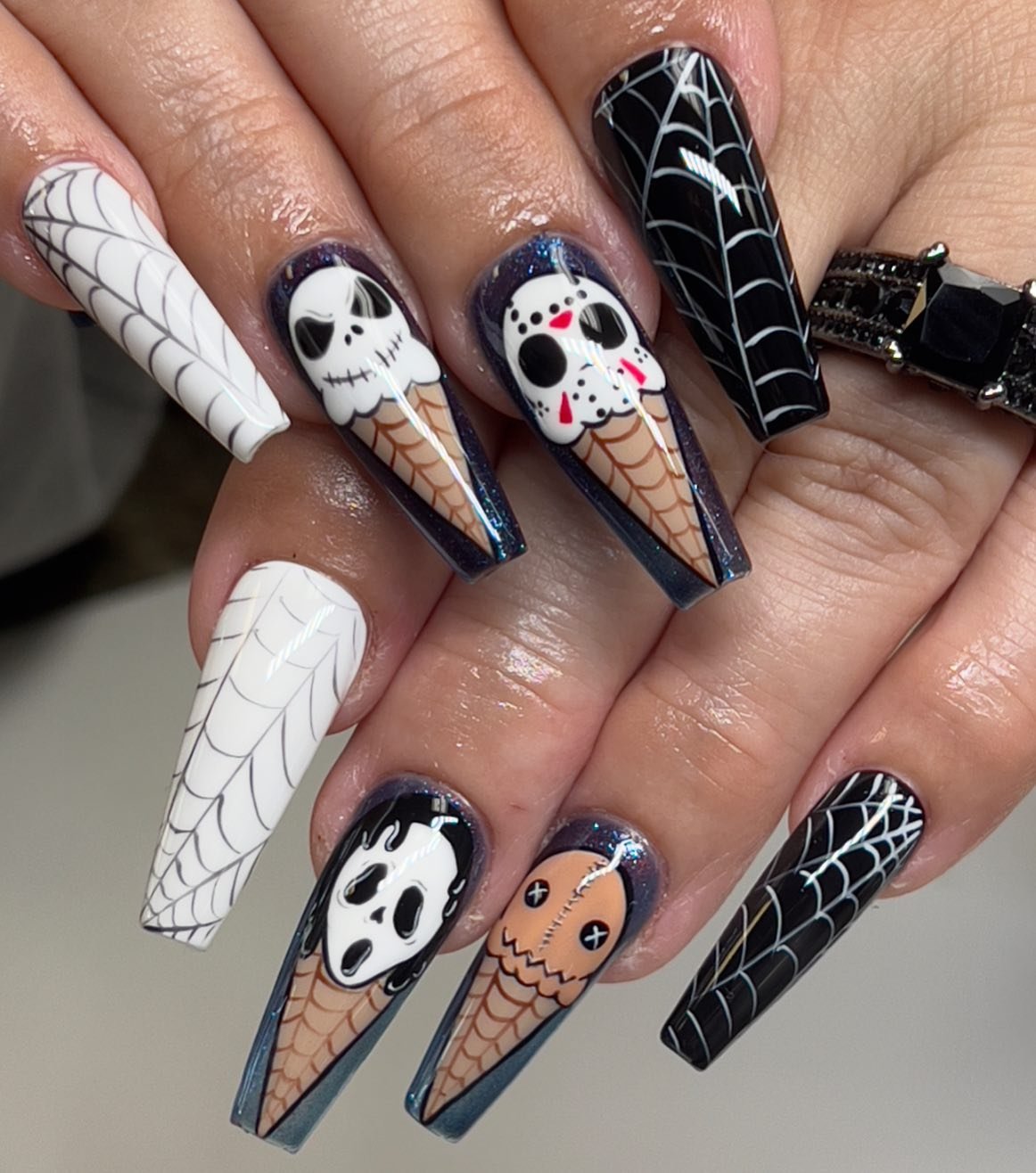 Long coffin nails feature white, black and orange Halloween imagery including webs and ghost-like faces.