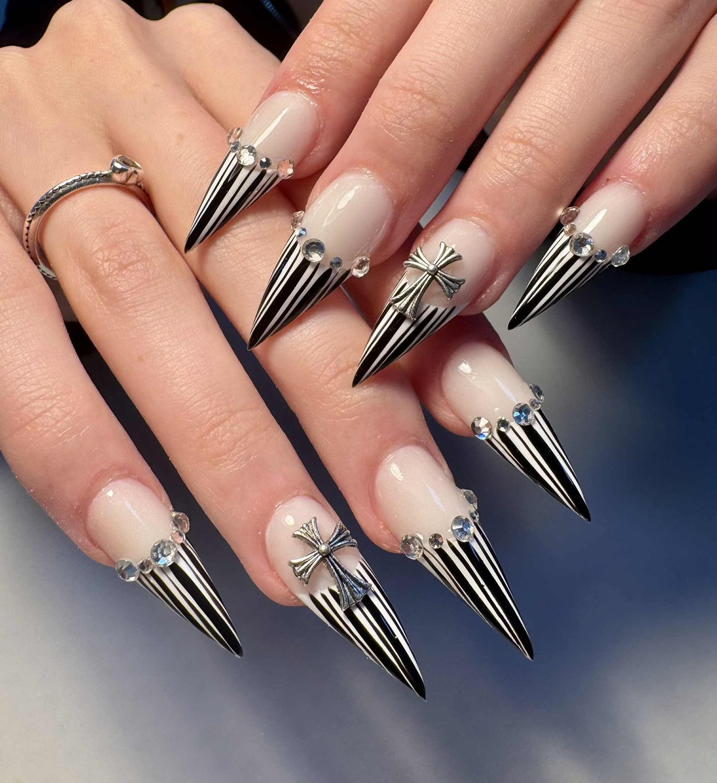Long nude stiletto nails are finished with dramatic silver chrome-like pointed spikes and metallic details.