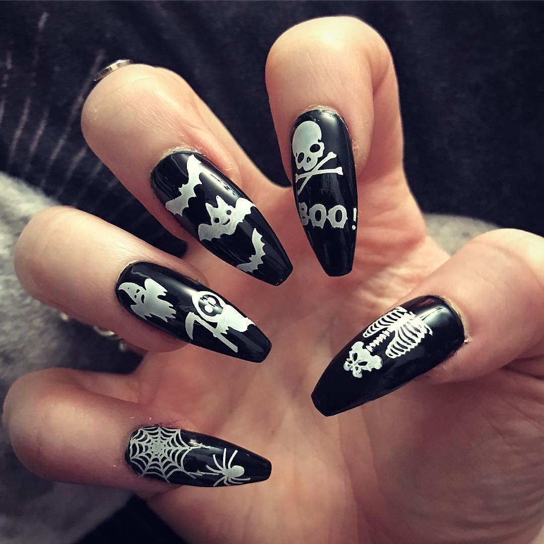 Long black nails are decorated with white skull imagery, bones, and spiderweb-style details.