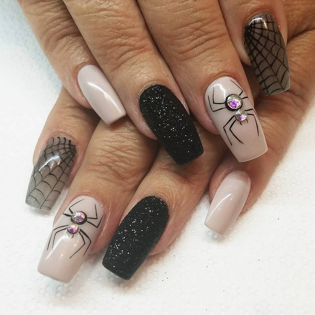 Short-to-medium nails combine white, black textured sections and small illustrated Halloween-style details.