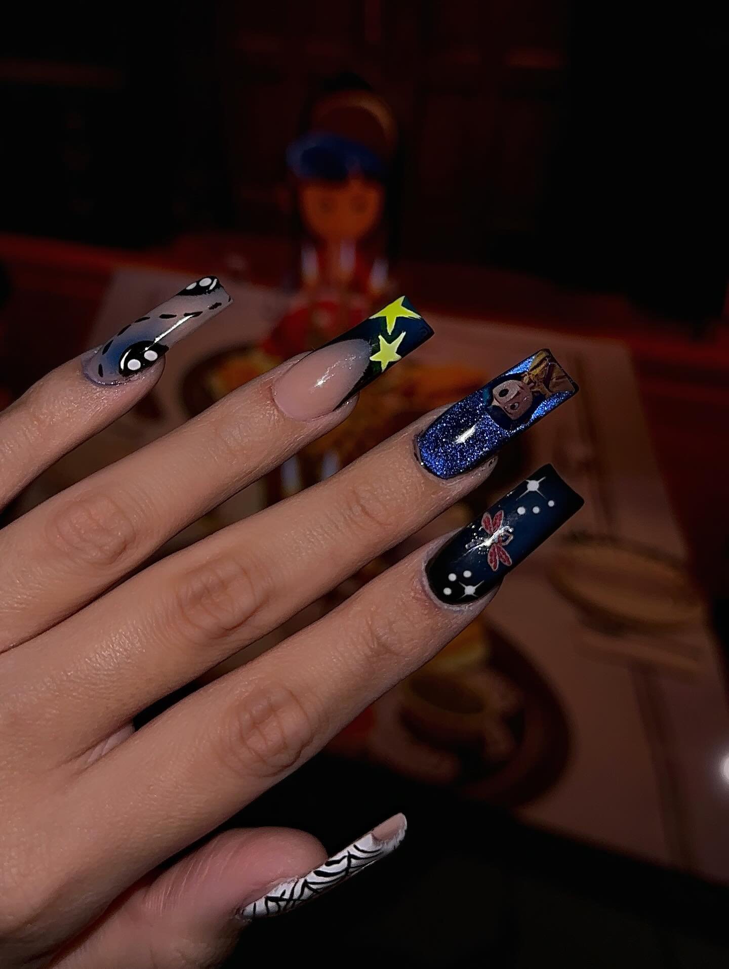Dark navy and black Halloween nails with stars, spooky graphics, and spiderwebs.