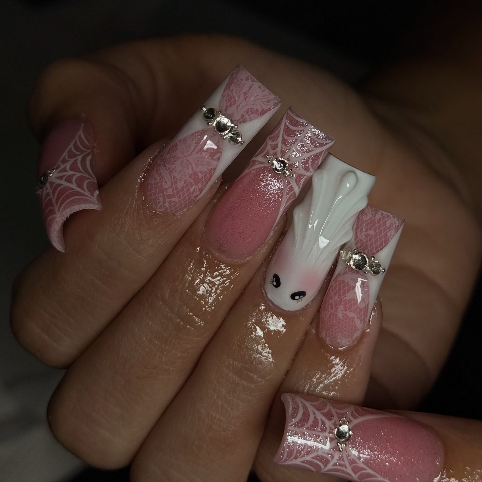 Pink and white square Halloween nails with lace, spiderwebs, a ghost, and rhinestones.