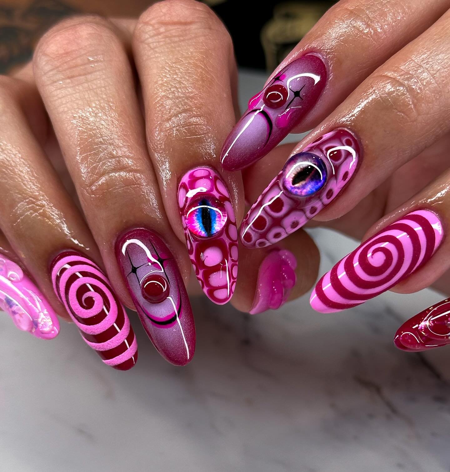 Vivid pink Halloween nails with raised eyeballs and spiral graphics.