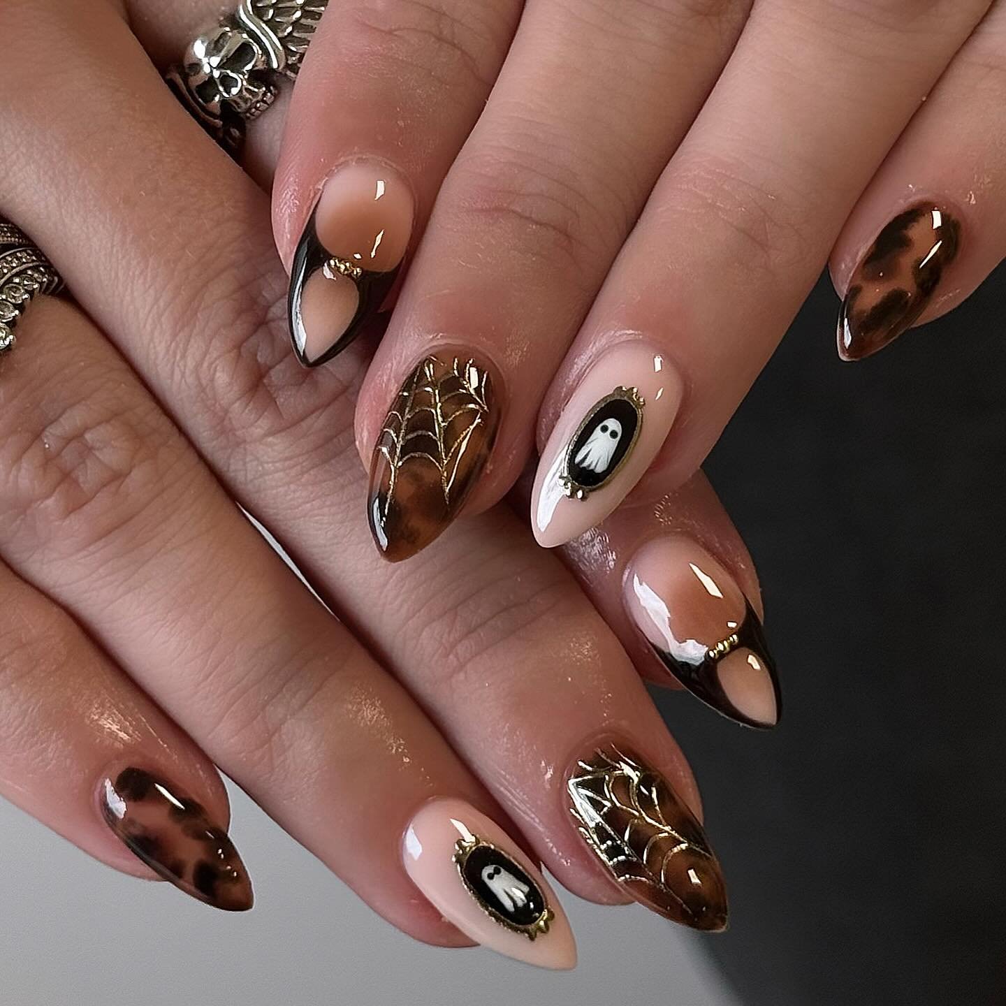 Brown tortoiseshell almond nails with gold spiderwebs and ghost accents.