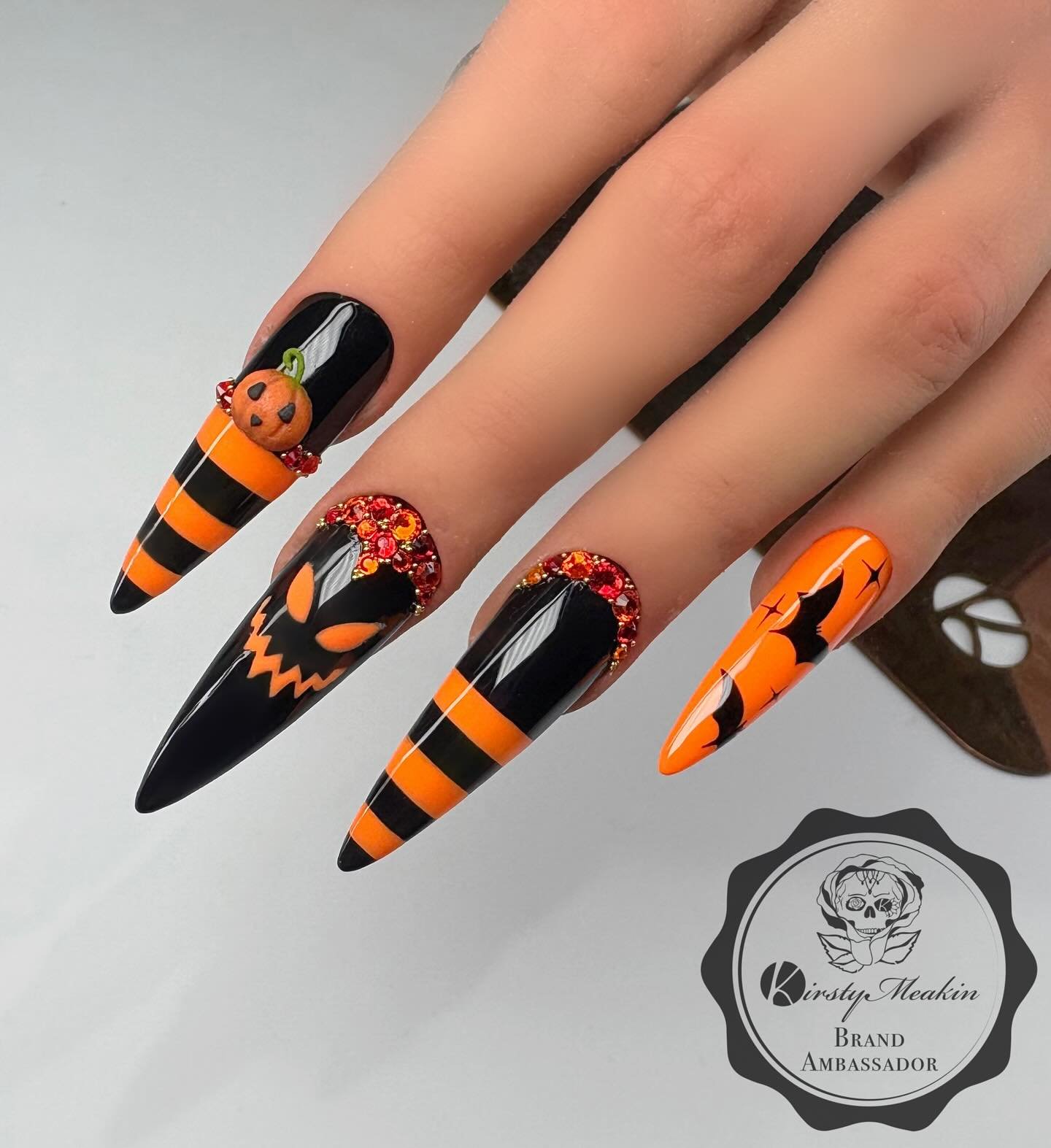Black and orange stiletto Halloween nails with pumpkins and striped accents.