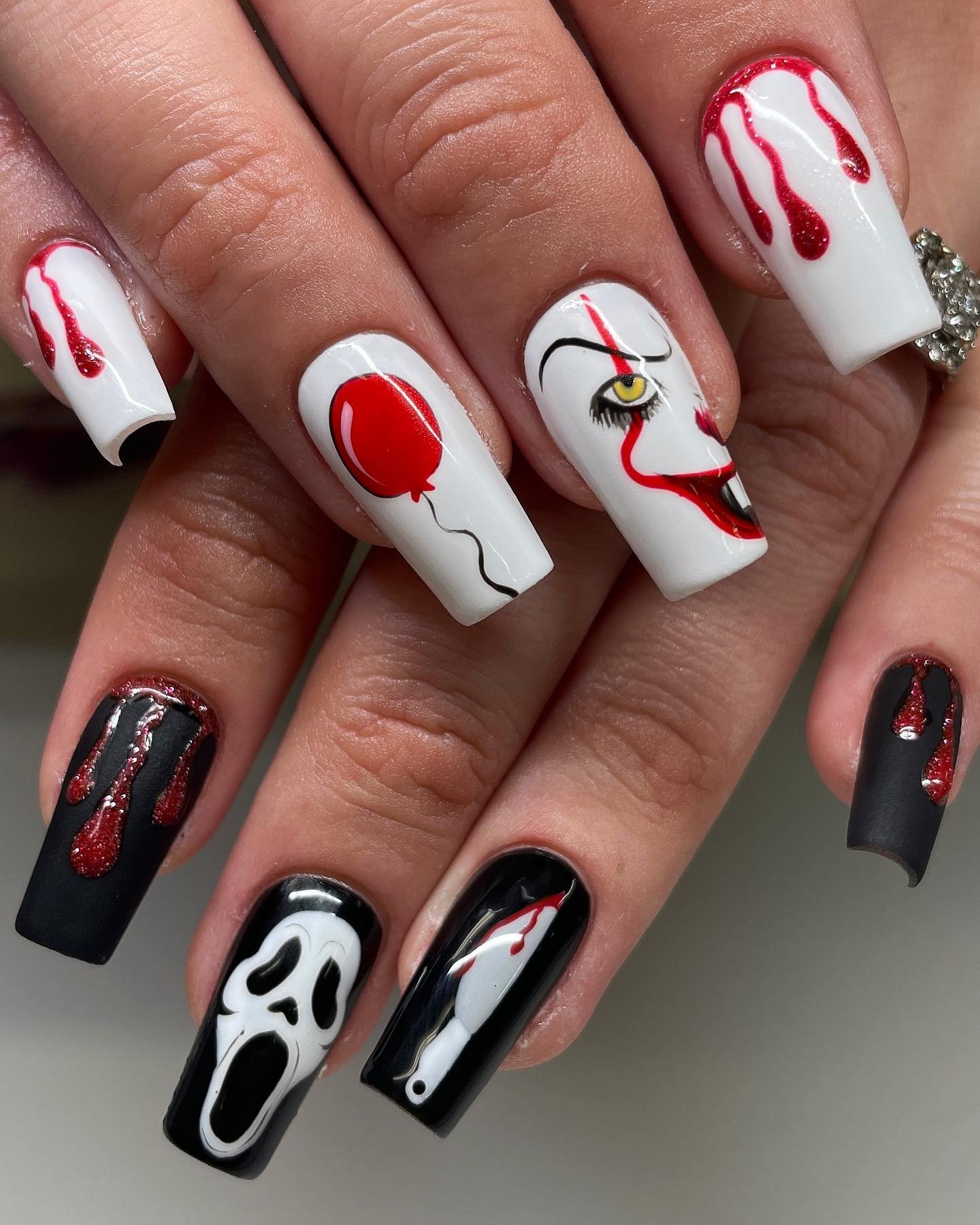 White and black horror-themed square nails with red details and spooky graphics.