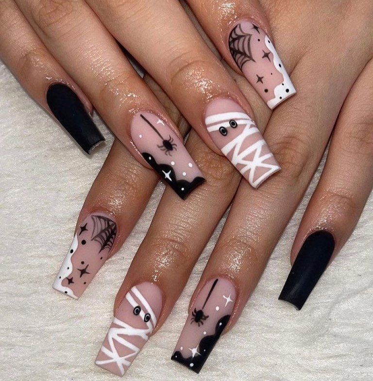Pink, black, and white square Halloween nails with mummies, spiders, and webs.