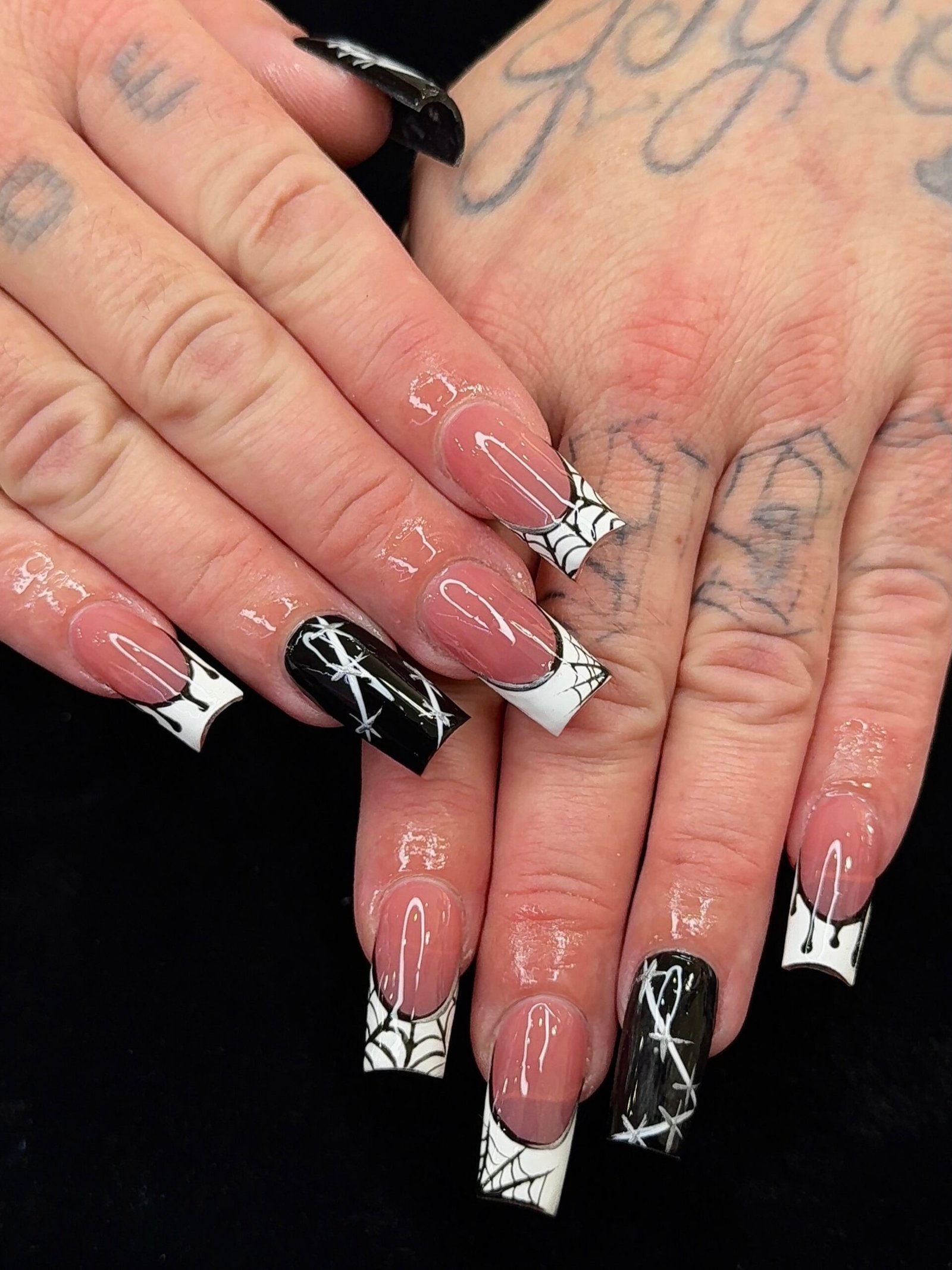 Sheer nude coffin Halloween nails with white spiderweb tips and black accents.
