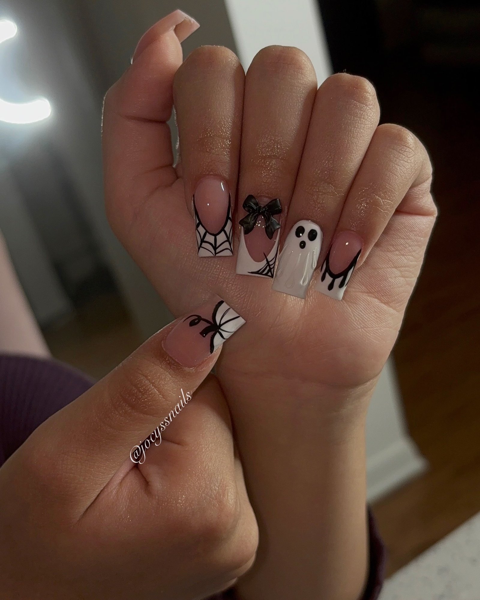 Short pink square Halloween nails with a ghost, bow, spiderwebs, and black drips.