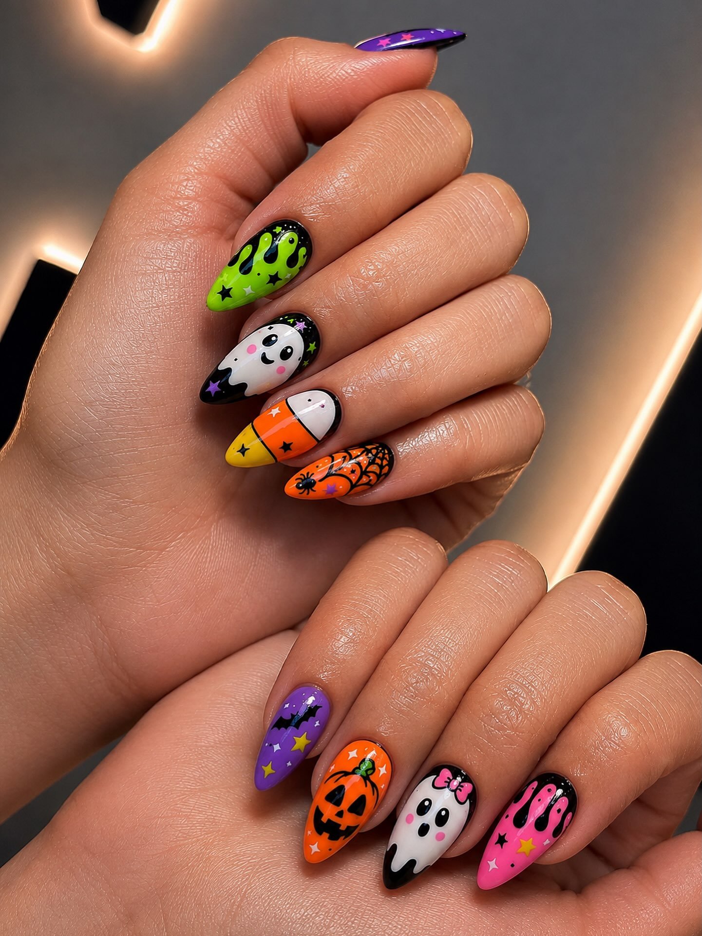 Colorful almond Halloween nails with ghosts, pumpkins, spiderwebs, stars, and drips.