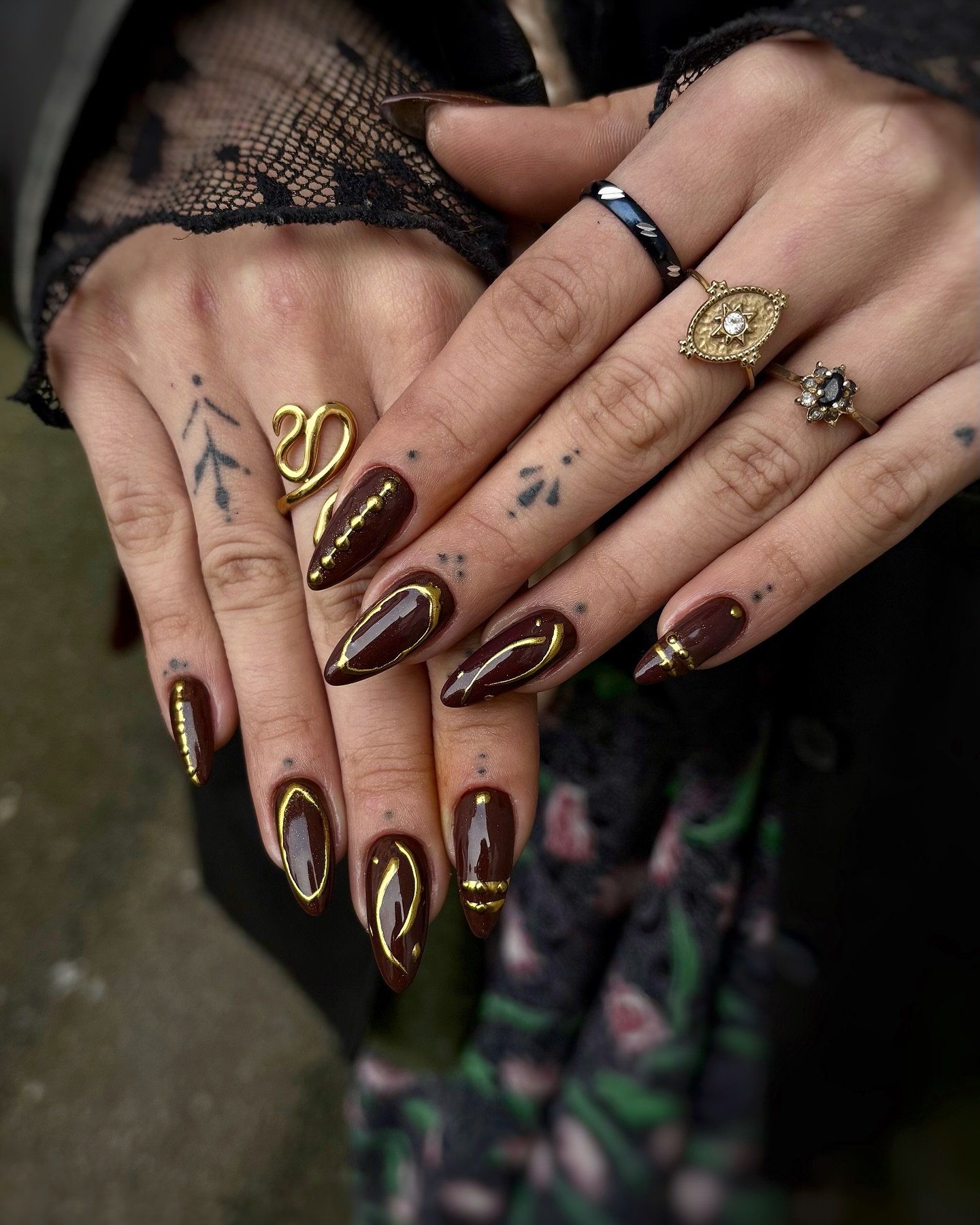 deep brown almond nails with gold outlines