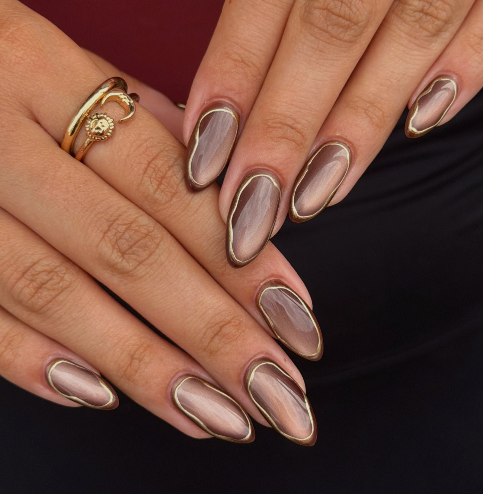 sheer nude almond nails with brown and gold outlines