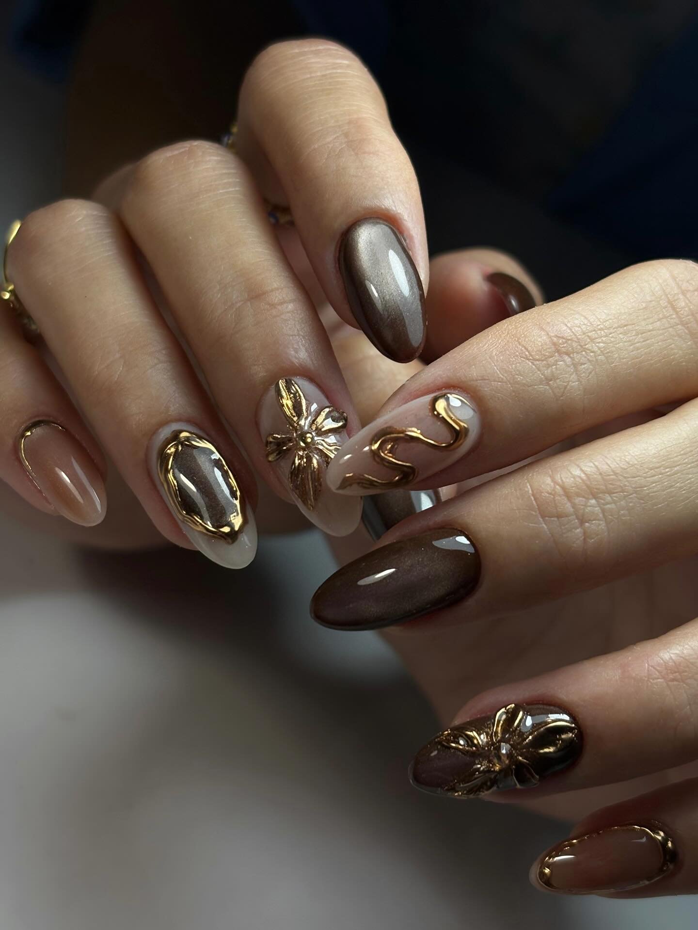 brown almond nails with raised gold floral details
