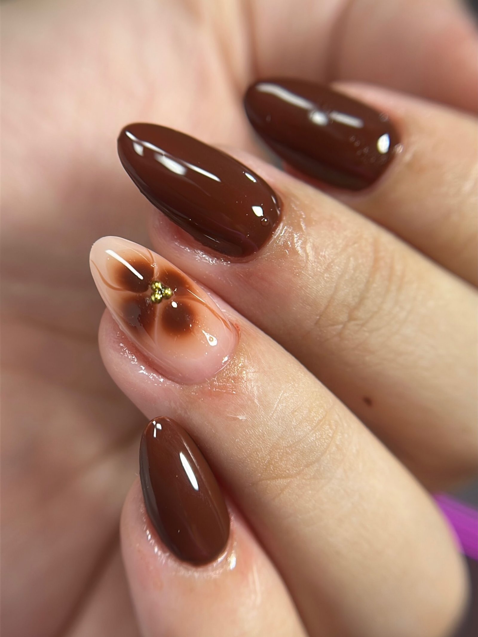 Glossy Chocolate Almond Nails with a Nude Floral Accent