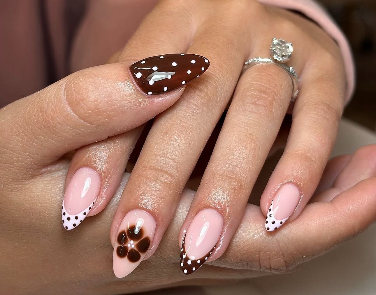 Pink Almond Nails with Brown Dotted Tips and a Floral Accent