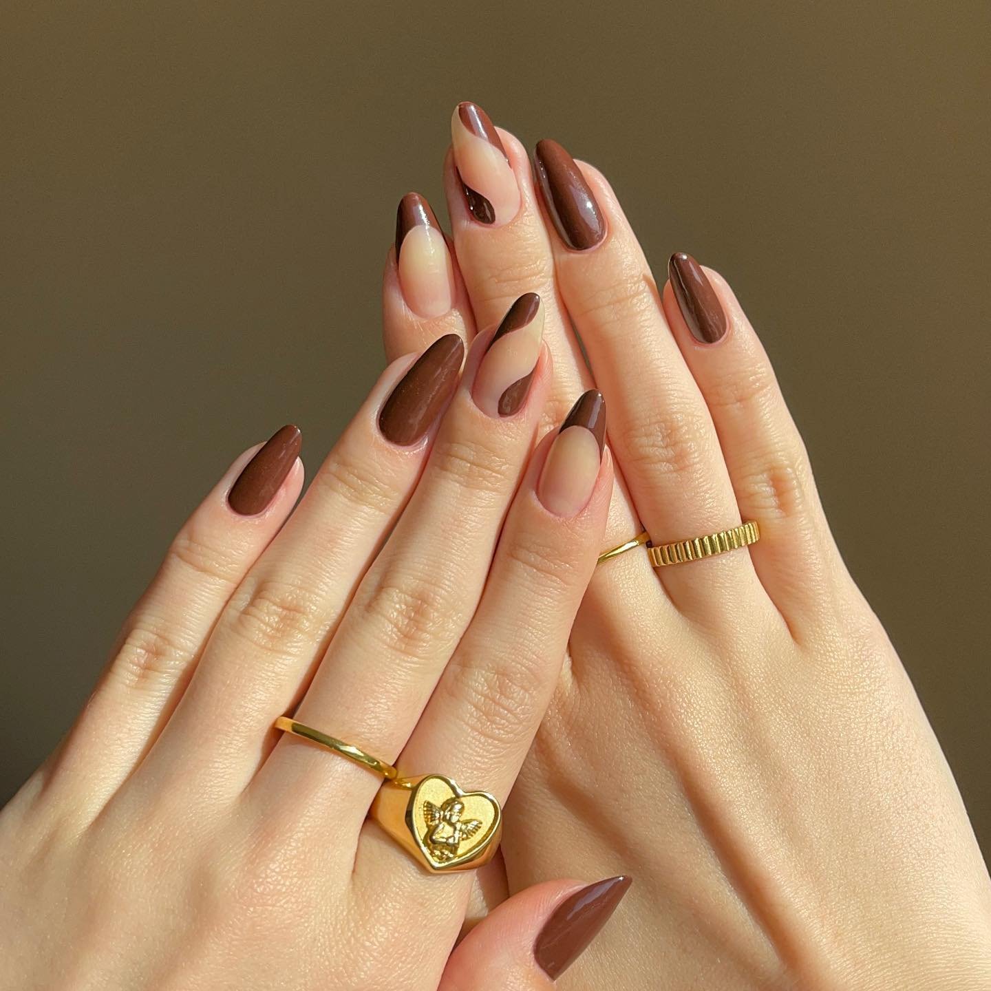 Neutral Almond Nails with Brown Curves and a Gold Heart Charm