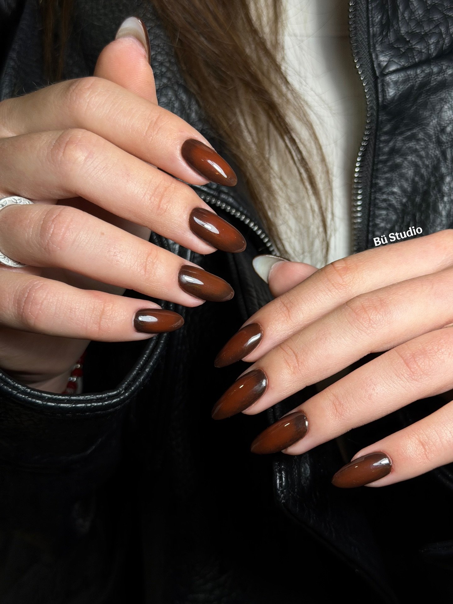 Glossy Brown Almond Nails with a Black Accent