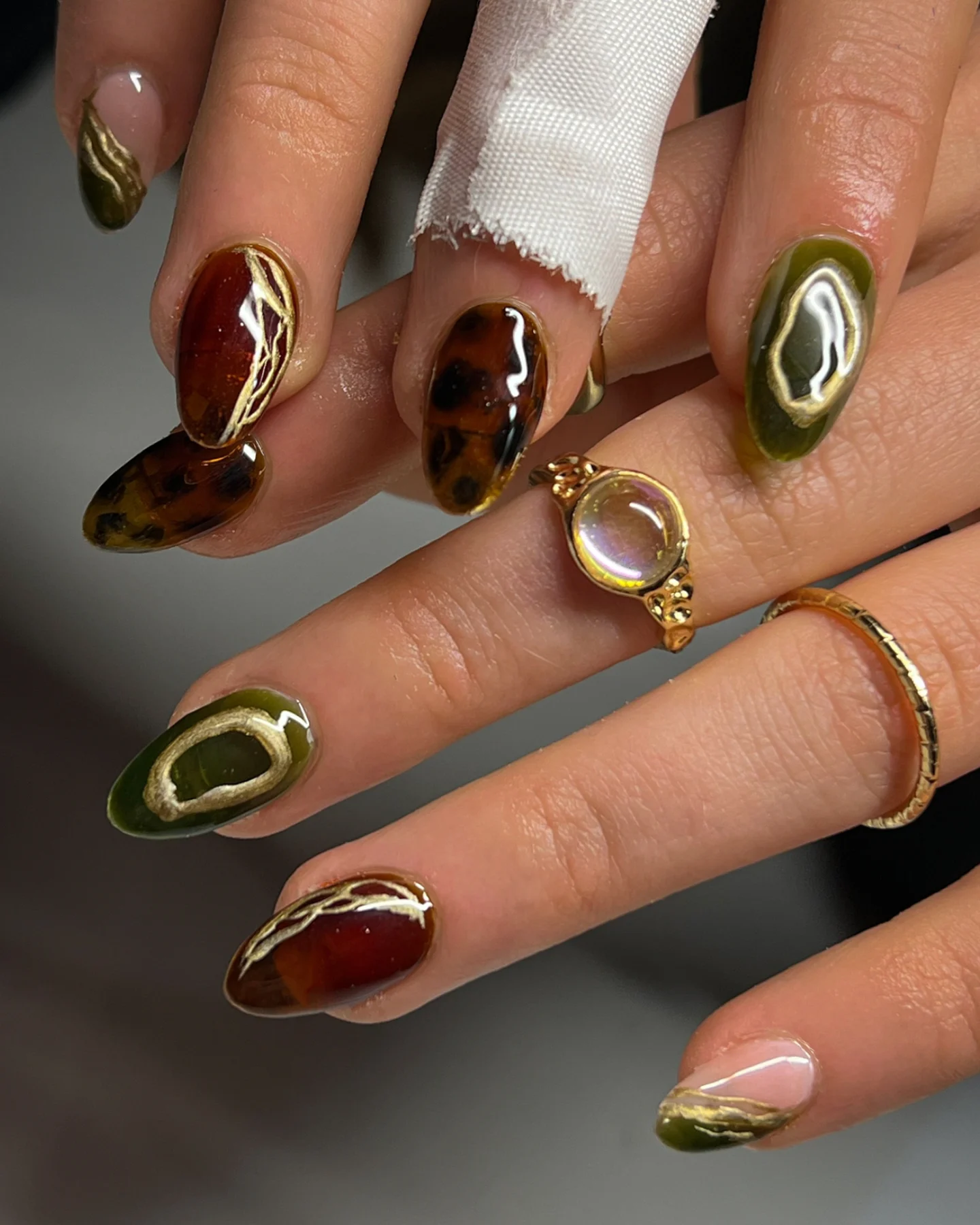 Mixed Brown Almond Nails with Gold and Green Accents