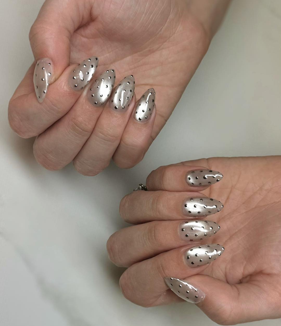 Silver Christmas nails idea 10: Sheer Almond Nails with Silver Glitter and Tiny Dark Accents
