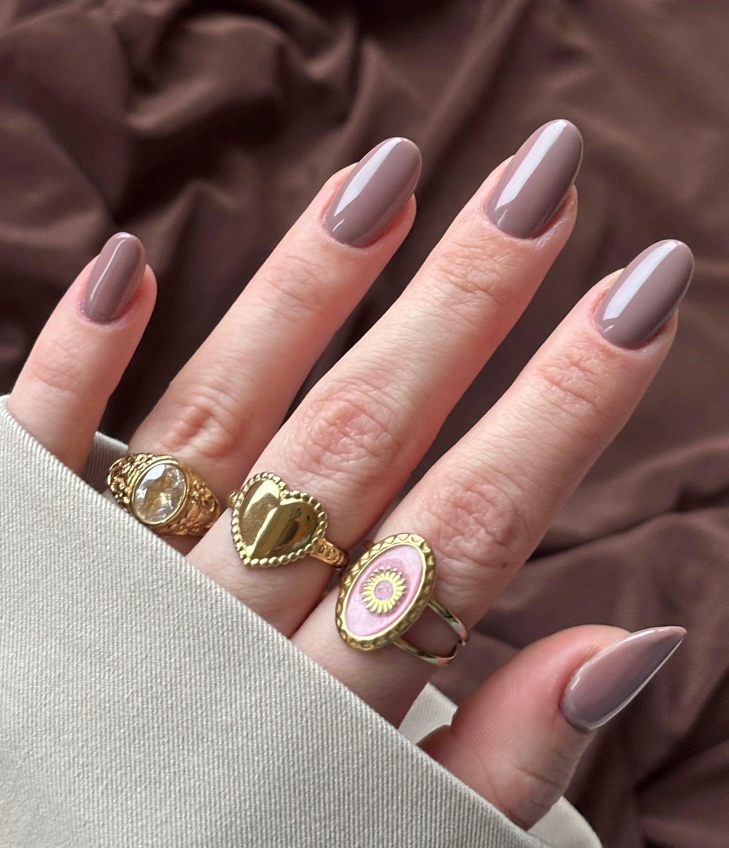 Long Taupe Nails with Gold Rings and Decorative Accents