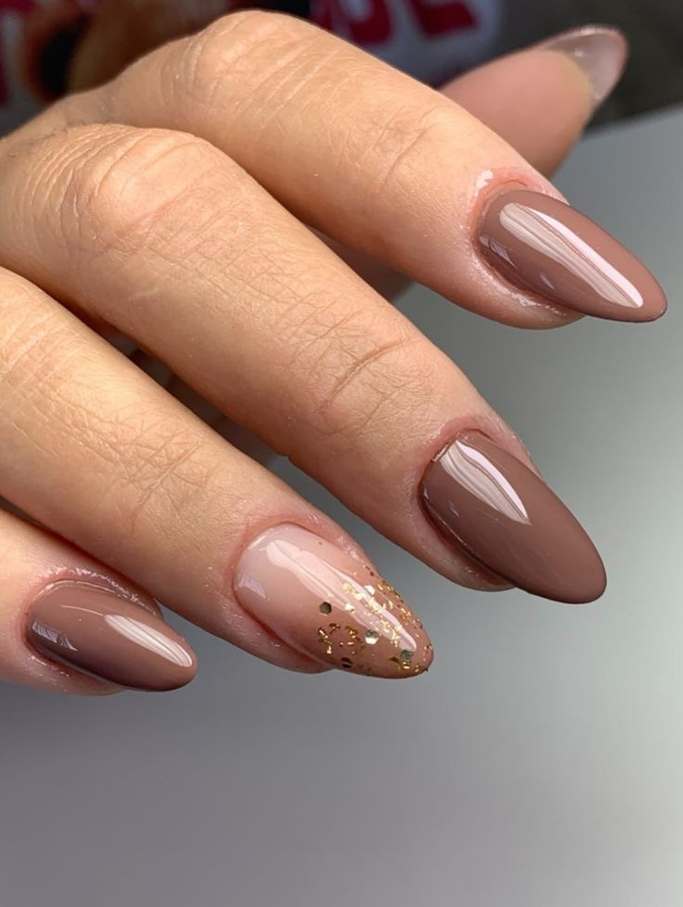 Long Glossy Taupe Almond Nails with a Glitter Accent
