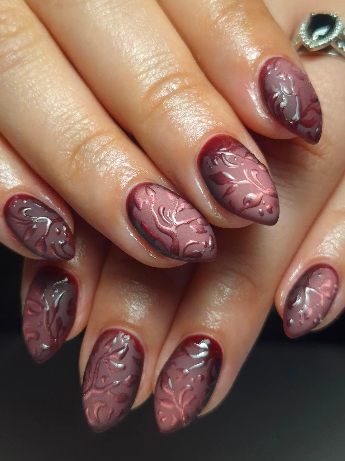 Medium-to-long almond nails combine a deep mauve base with glossy raised-looking abstract swirls across the surface.