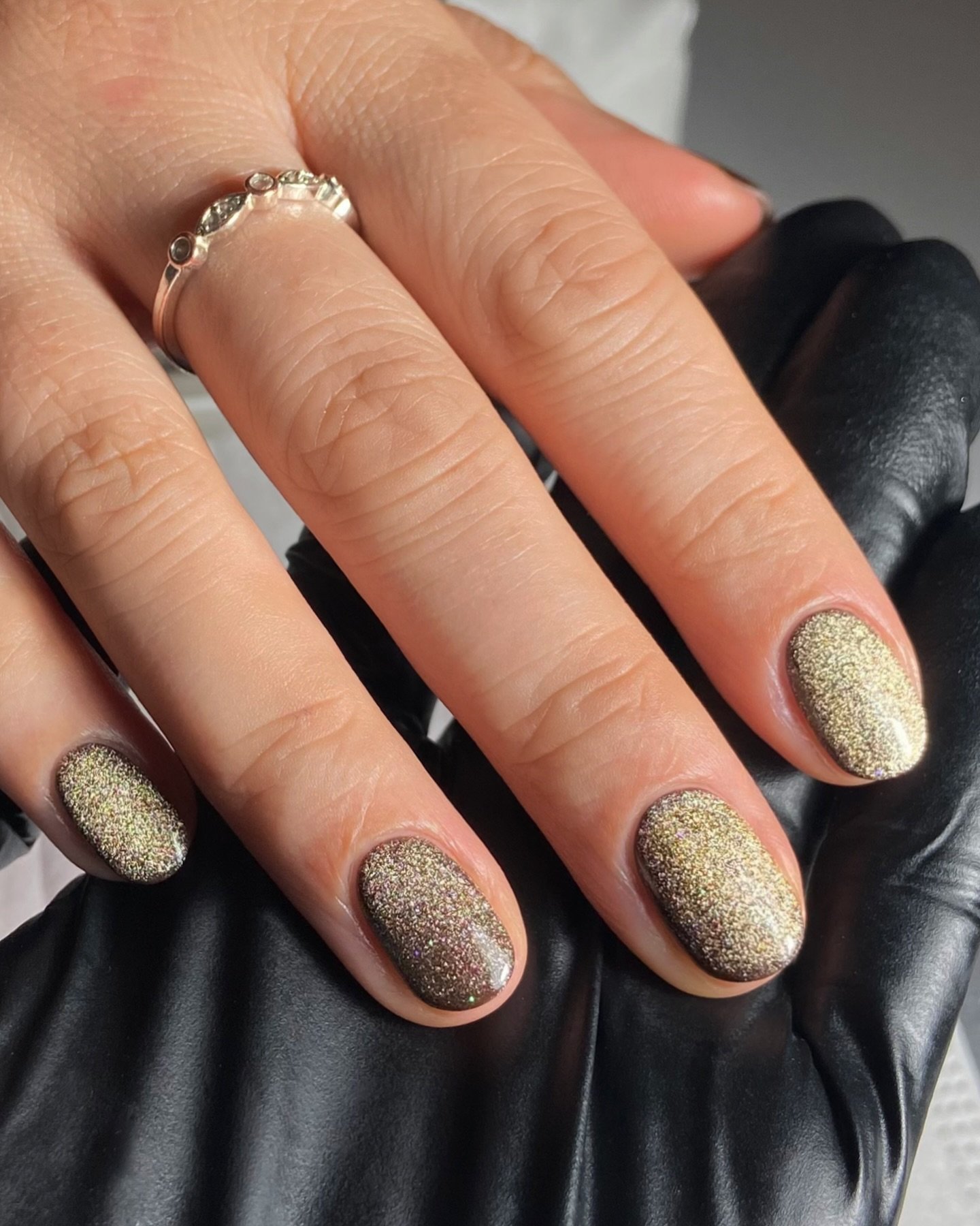 Medium almond nails are coated in a soft taupe shade with a fine reflective shimmer that catches the light.