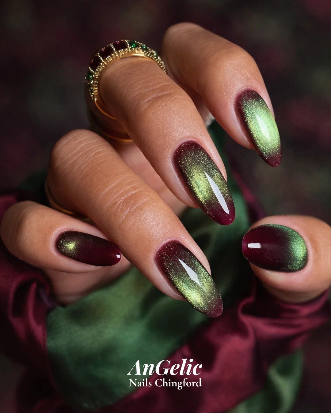 Long almond nails alternate deep burgundy and green tones with a luminous velvet-like cat-eye glow.