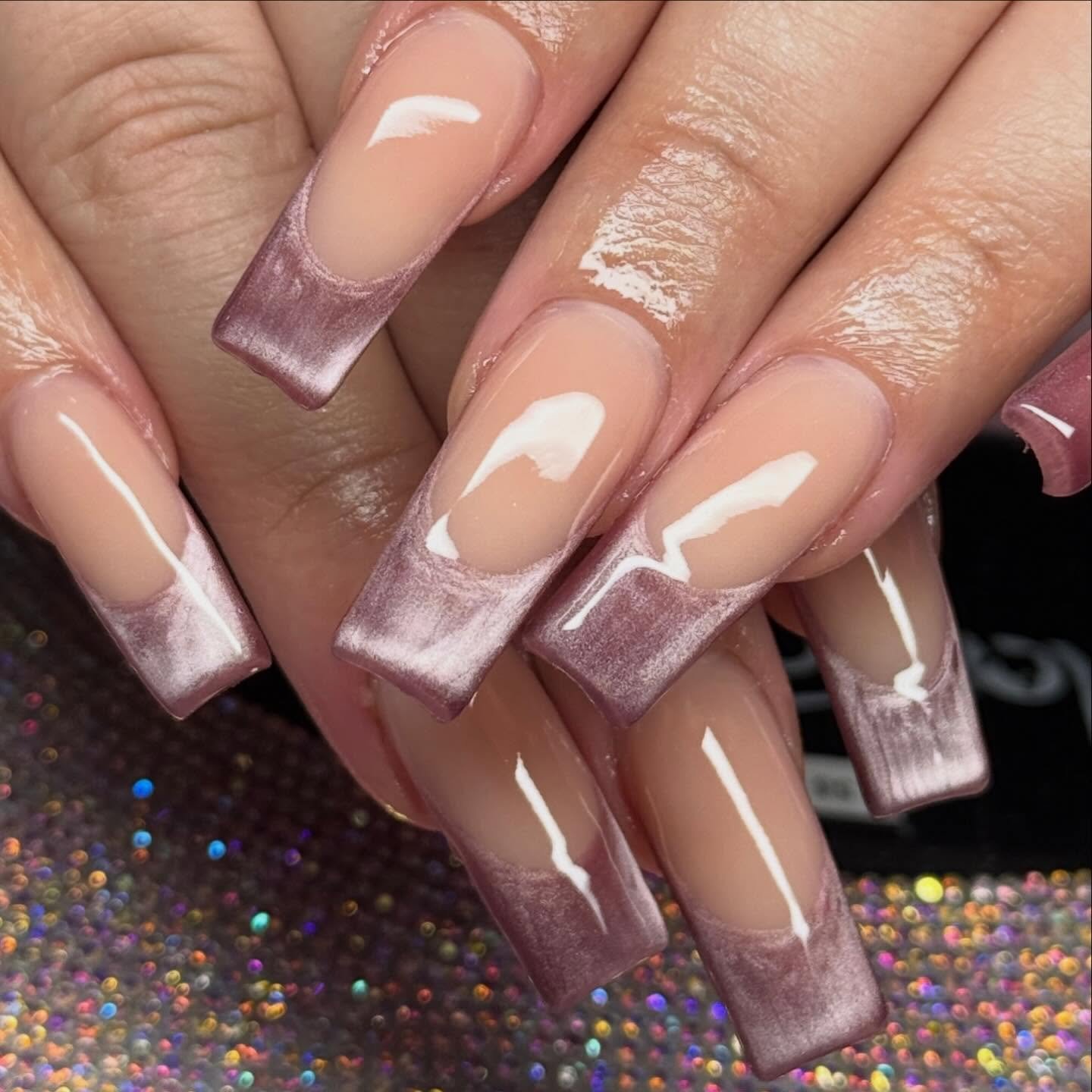 Long square nails feature a clear pink base with metallic mauve-purple French-style tips and glossy highlights.