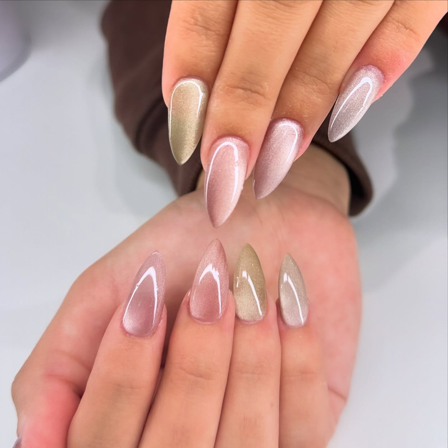 Long almond nails combine sheer pink and champagne-toned finishes with clean glossy surfaces.