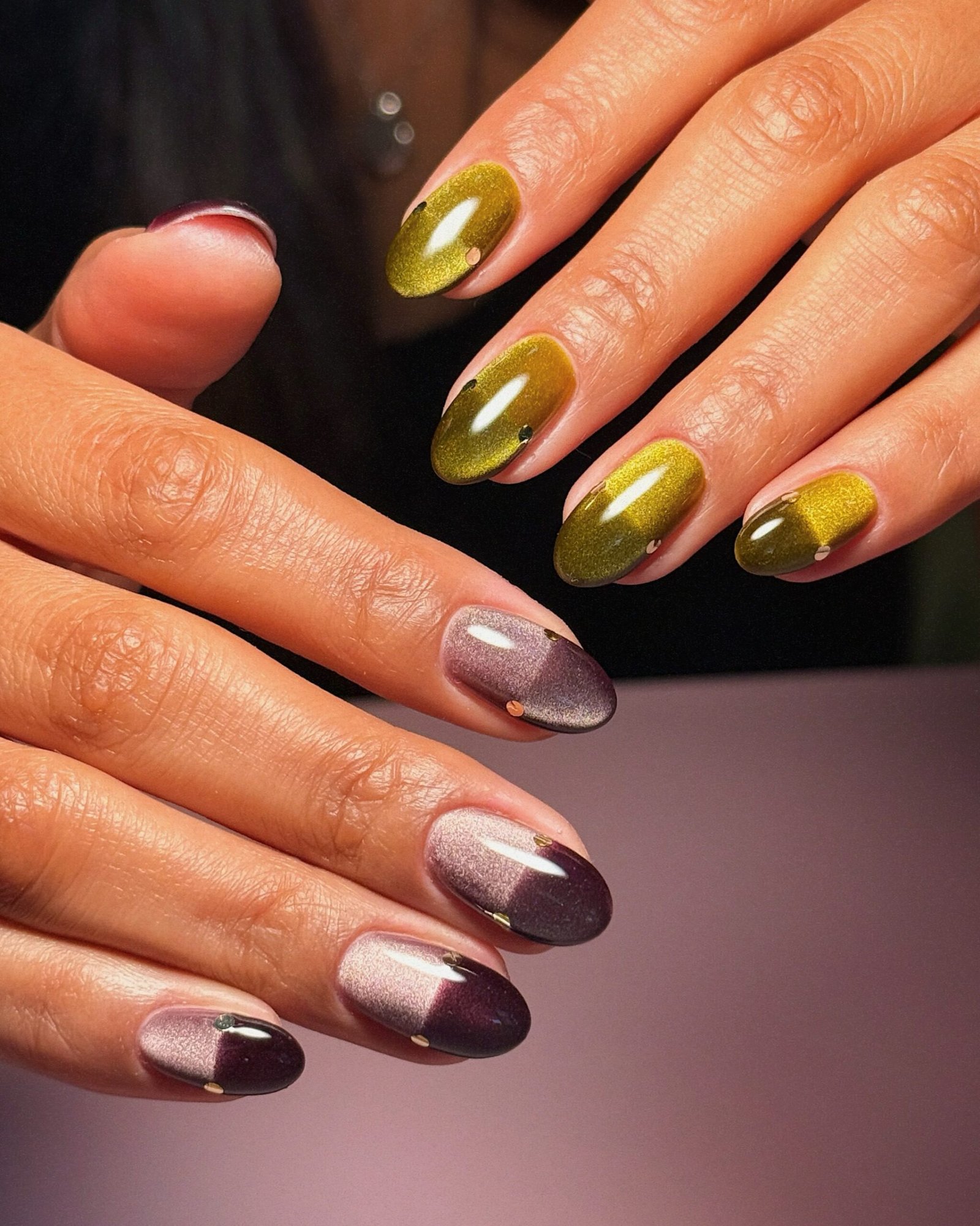 Long almond nails use a translucent lavender base decorated with small gold and crystal-like embellishments.