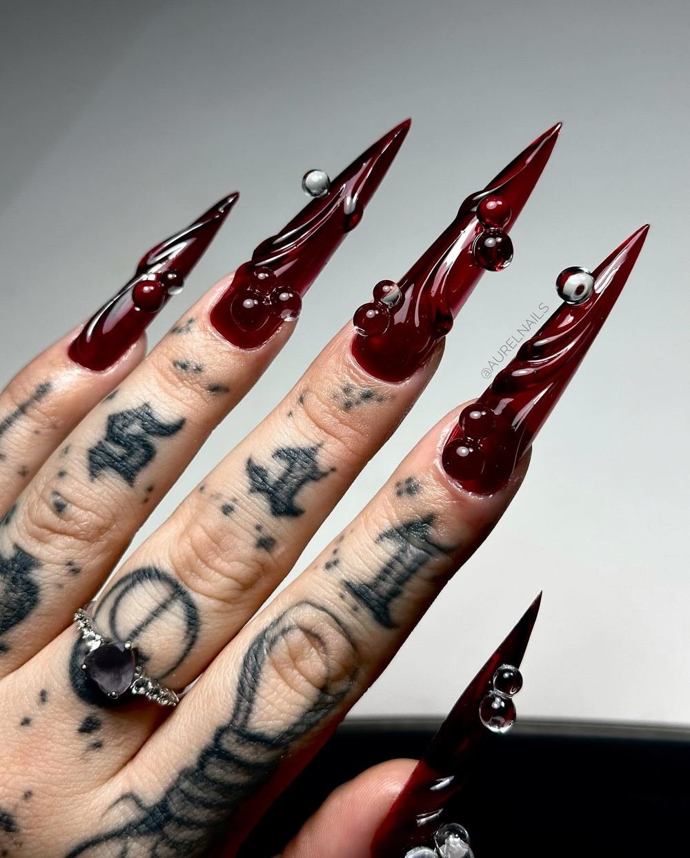 Deep Red Stiletto Nails with Metallic Charms